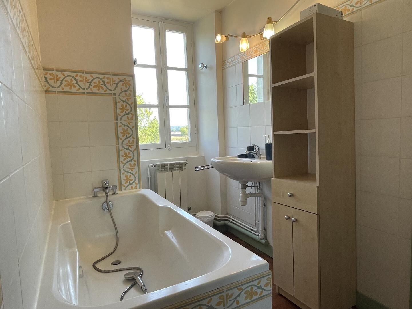 Un baño con bañera, lavamanos y ventana.