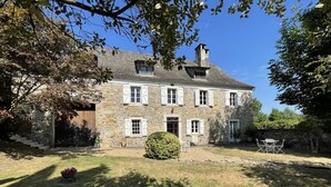 A stone house with a front door, a small front yard, and a dining area with outdoor furniture. - CHEZ CAZALETS - SUSMIOU (SUSMIOU)