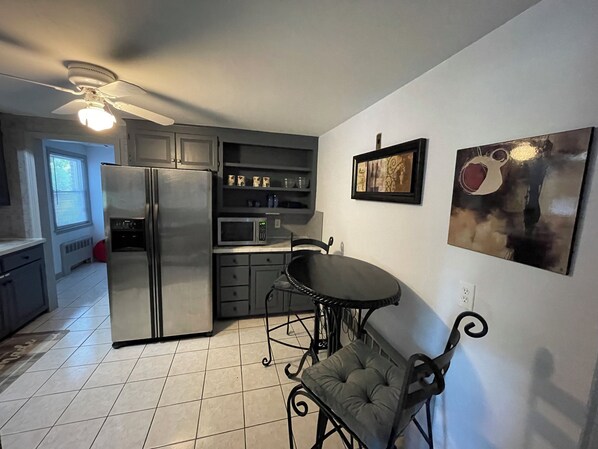 A compact kitchen with a refrigerator, microwave, and a dining area with a chair and table.