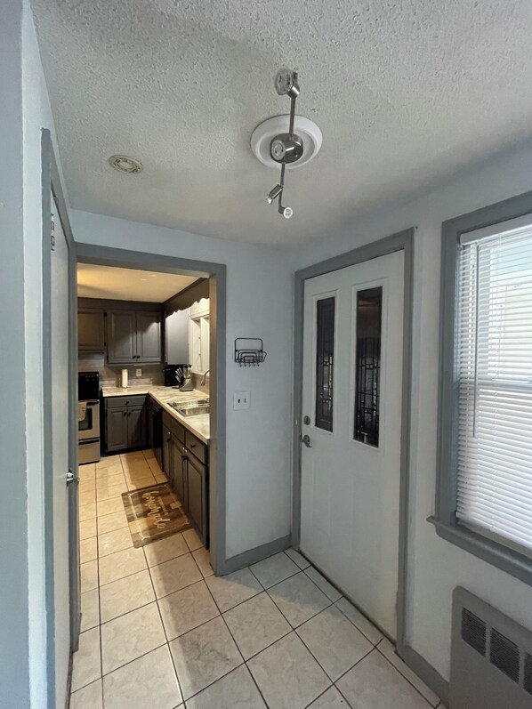 A narrow hallway with a kitchen area at the end, featuring cabinets, a sink, and a ceiling fan.