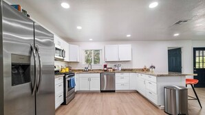 Una cocina moderna con armarios blancos, electrodomésticos de acero inoxidable y encimera de granito.
