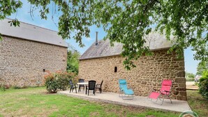 A stone building with a patio area featuring outdoor seating and a table.