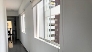 Un pasillo con una ventana, una puerta y el reflejo de edificios.
