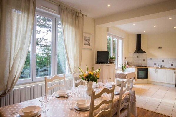 A dining area with a table set for four, a television, and a kitchen in the background.