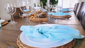 A dining table set with plates, glasses, and cutlery, surrounded by woven placemats and a blue cloth napkin. - Venice Escape 6 Minutes to Beach & near YMCA Pool (Venice)