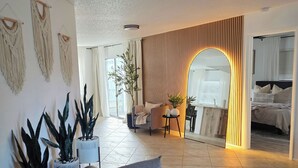 A spacious living room with a sofa, potted plants, a coffee table, and a large mirror reflecting the room. - Venice Escape 6 Minutes to Beach & near YMCA Pool (Venice)