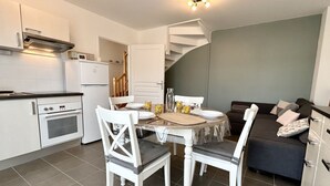 A compact kitchen with white cabinets, a built-in oven, and a dining area with a round table and four chairs.