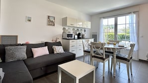 A modern living room with a sofa, a coffee table, and a dining area with chairs and a table.