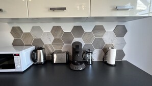 A kitchen with a microwave, toaster, coffee maker, and kettle on a black countertop.