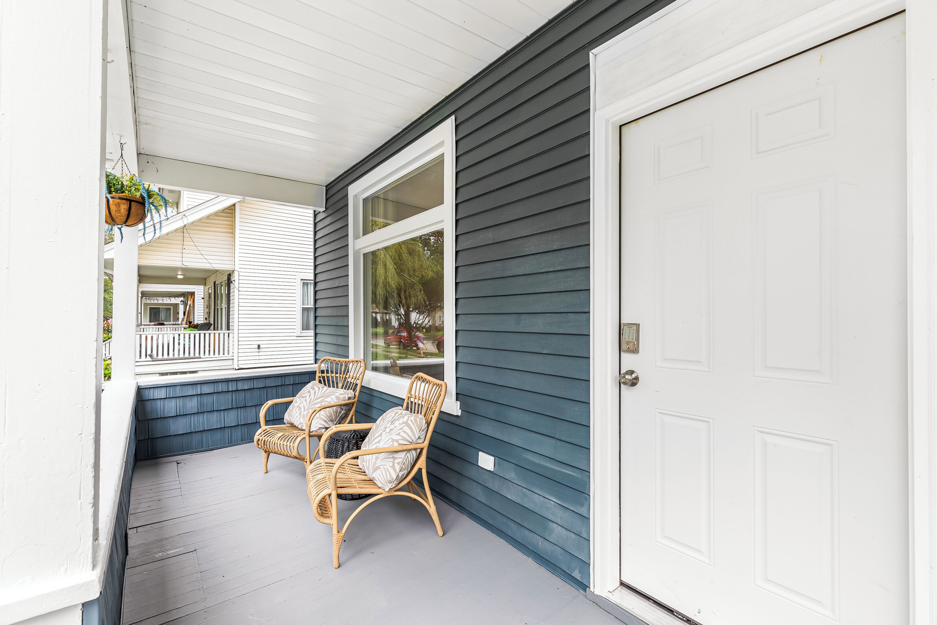 A porch with wicker chairs and a white door.