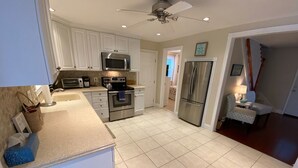 Una cocina moderna con armarios blancos, electrodomésticos de acero inoxidable y piso de baldosas.