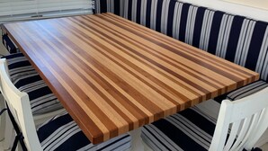 Un comedor con una mesa de madera y bancos tapizados a rayas.