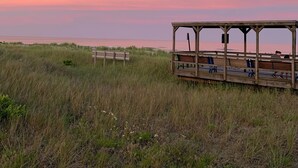 Un pabellón de madera con bancos que da a una playa al atardecer.