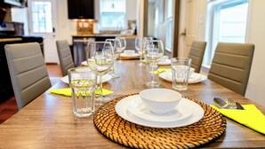 Une table à manger dressée avec des assiettes, des verres et des couverts, avec une cuisine en arrière-plan.