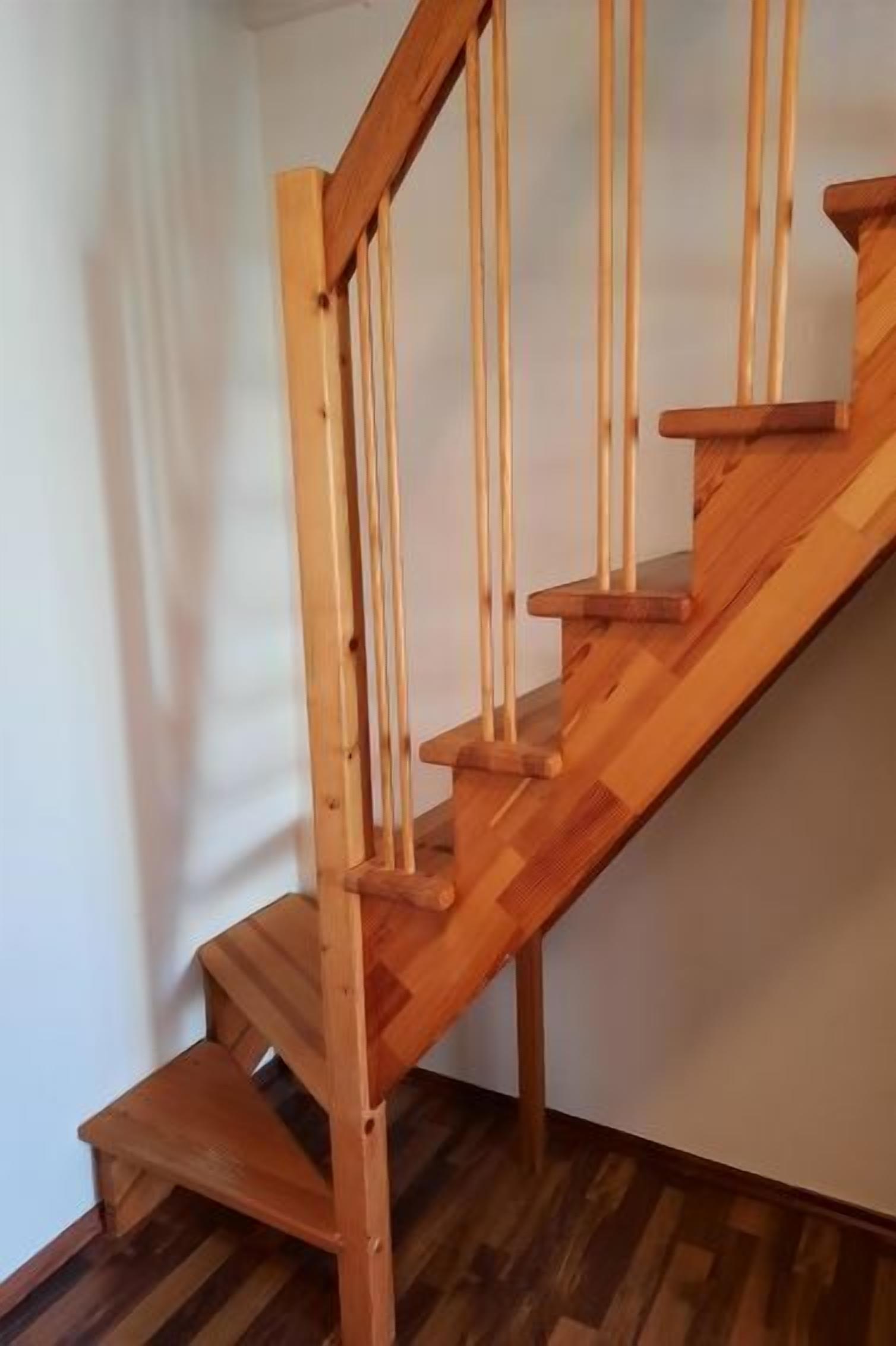 Een houten trap met een leuning en een tussenverdieping.