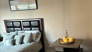 Un dormitorio con una cama, una mesita de noche con velas y un cuadro enmarcado en la pared.