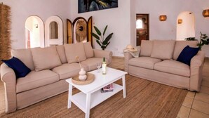 A living room with two beige sofas, a white coffee table, and a painting on the wall.