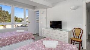 Une chambre avec deux lits, une télévision et une chaise.