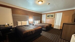 A hotel room with two beds, a desk, and a dresser.
