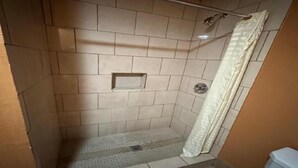 A small, tiled shower area with a shower curtain and a showerhead.