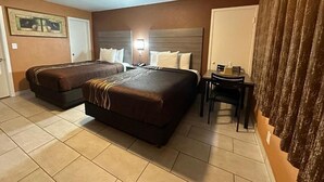 A hotel room with two beds, a desk, and a chair.