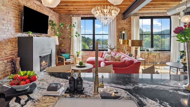 A modern living room with a fireplace, a large window with a view, and a chandelier. - Top of the Town | Luxury 2BR Adults-Only · Downtown Burnsville · Walk Everywhere (Burnsville)