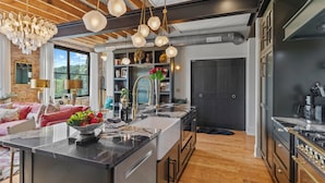 A modern kitchen with a central island, stainless steel appliances, and a wooden ceiling. - Top of the Town | Luxury 2BR Adults-Only · Downtown Burnsville · Walk Everywhere (Burnsville)