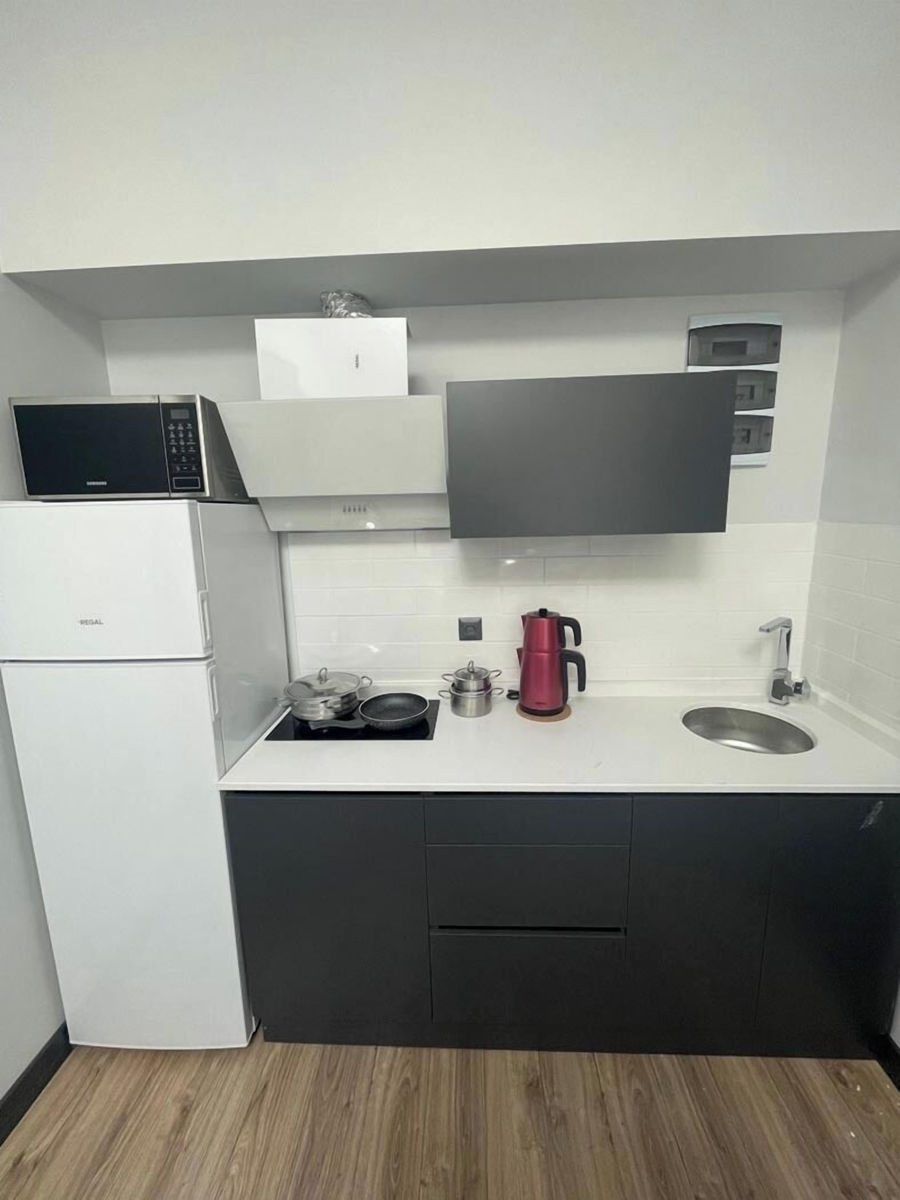 A compact kitchen with a refrigerator, microwave, stove, and a coffee maker.