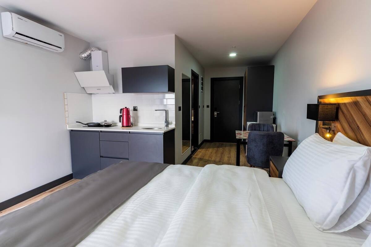 Ett hotellrum med en säng, ett litet pentry, ett skrivbord och en stol.