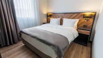 A hotel room with a large bed, wooden headboard, two bedside tables, and a nightstand.