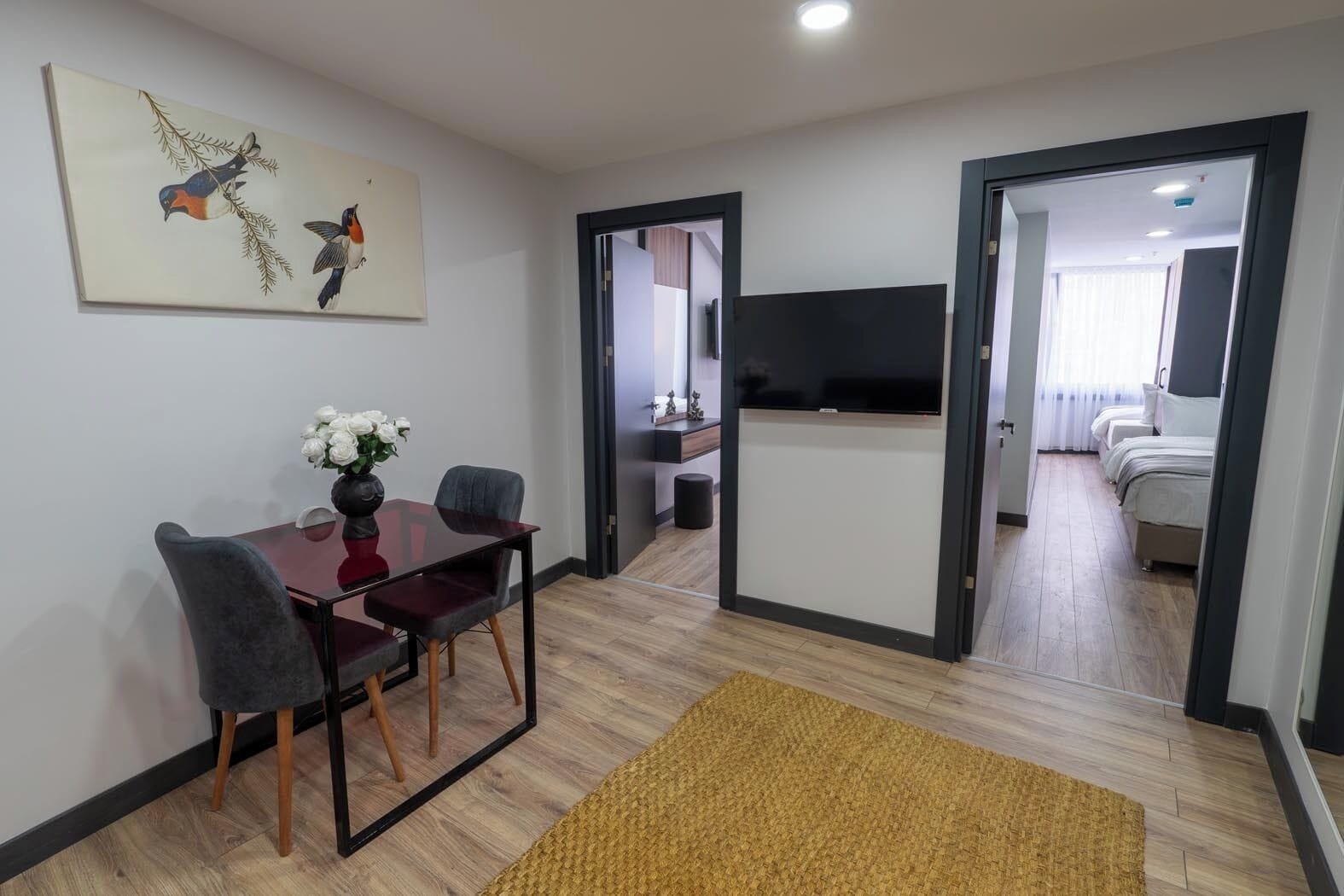 Una habitación de hotel moderna con comedor, televisor y cama.