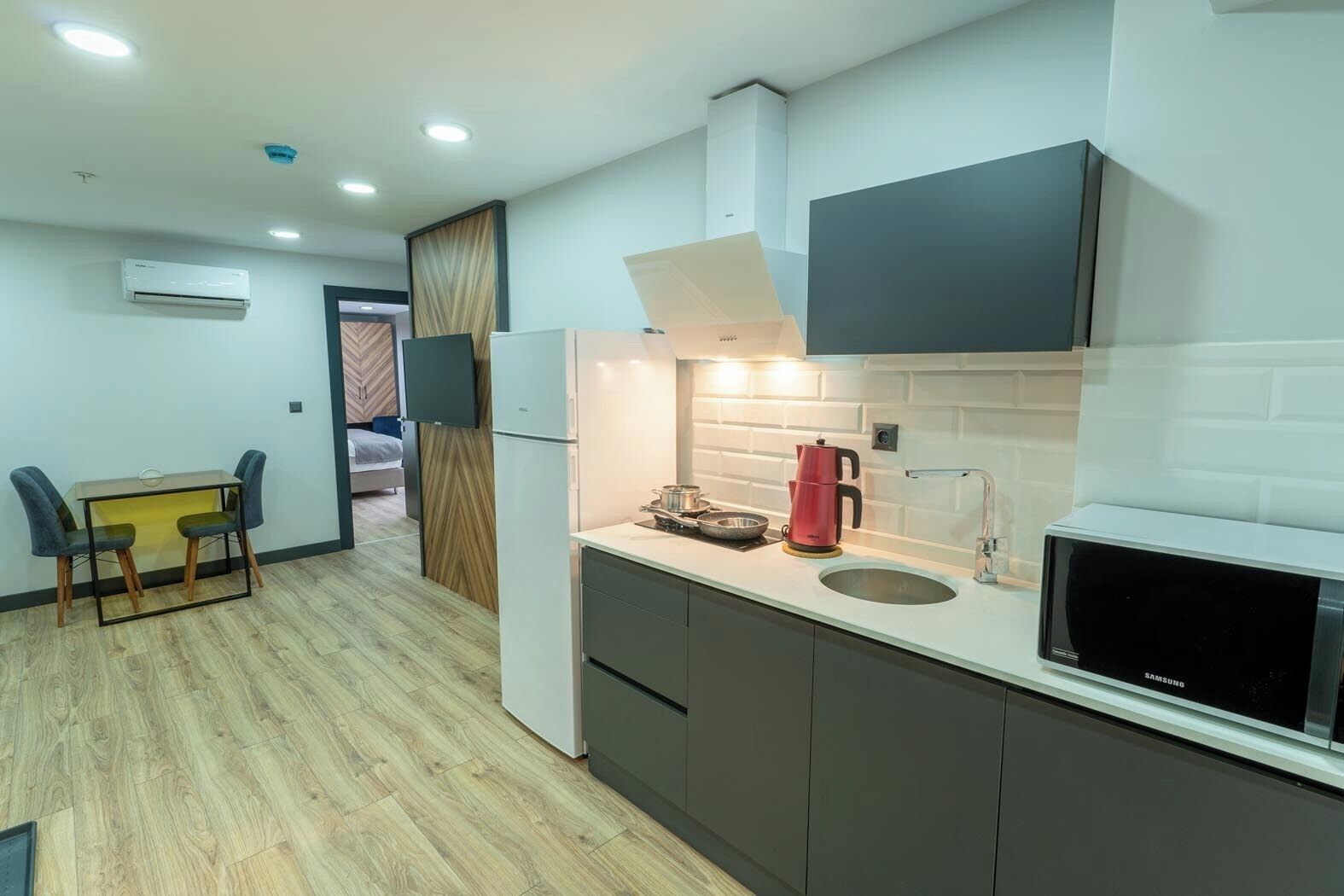 A compact kitchen with a microwave, sink, and a small dining area with chairs.