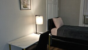 A small, neatly arranged bedroom with a bed, a desk, and a chair.