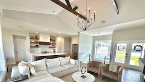 A modern living room with a white sofa, a round coffee table, and a chandelier.