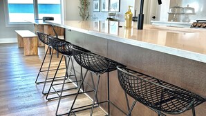A modern kitchen with a bar area, wooden flooring, and a view of the ocean.