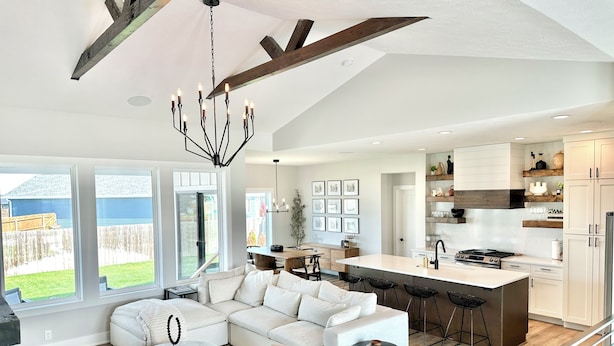 A modern kitchen with a large island, white cabinetry, and a dining area with a white sofa and chairs.