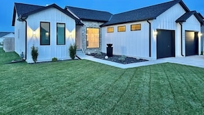 A modern two-story house with a well-maintained lawn, a stone facade, and a garage with a black door.