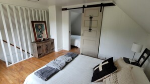 A bedroom with a bed, a dresser, a painting, and a door leading to another room. - The Red House -  modern beautiful Scandinavian style cozy cottage! (Chassell)