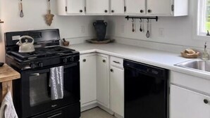 A compact kitchen with white cabinets, a black stove, and a dishwasher. - The Red House -  modern beautiful Scandinavian style cozy cottage! (Chassell)
