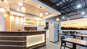 Una zona de bar moderna amb un taulell de recepció de fusta, amples prestatges plens de botelles i una zona de seients amb taules i cadires.