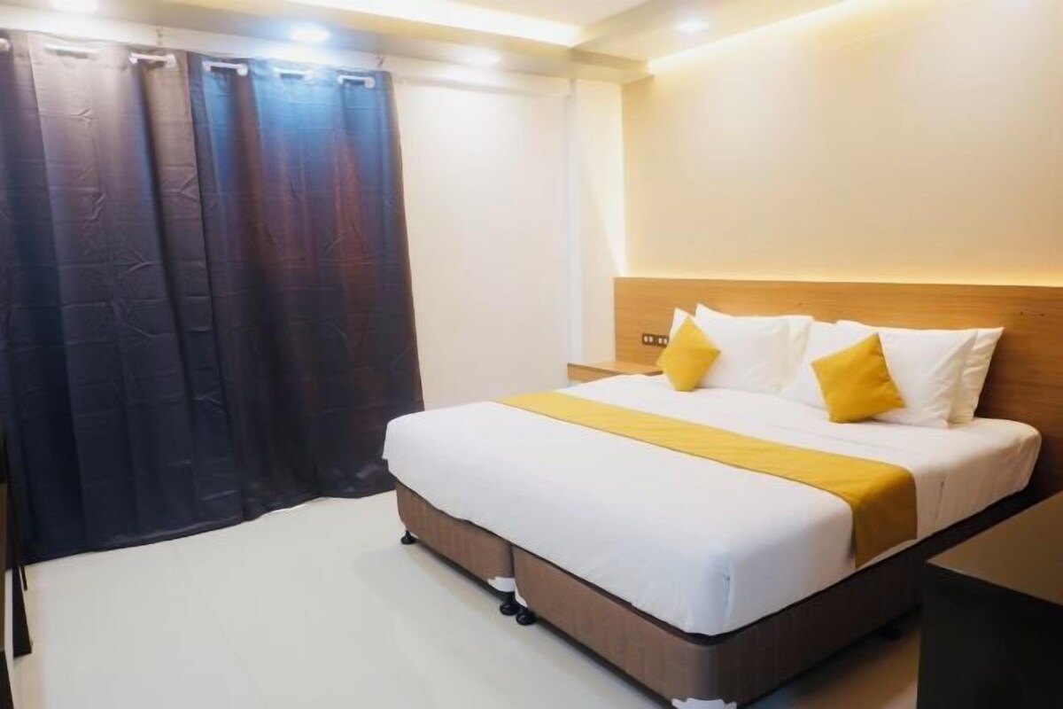 A hotel room with a bed, curtains, and a nightstand.