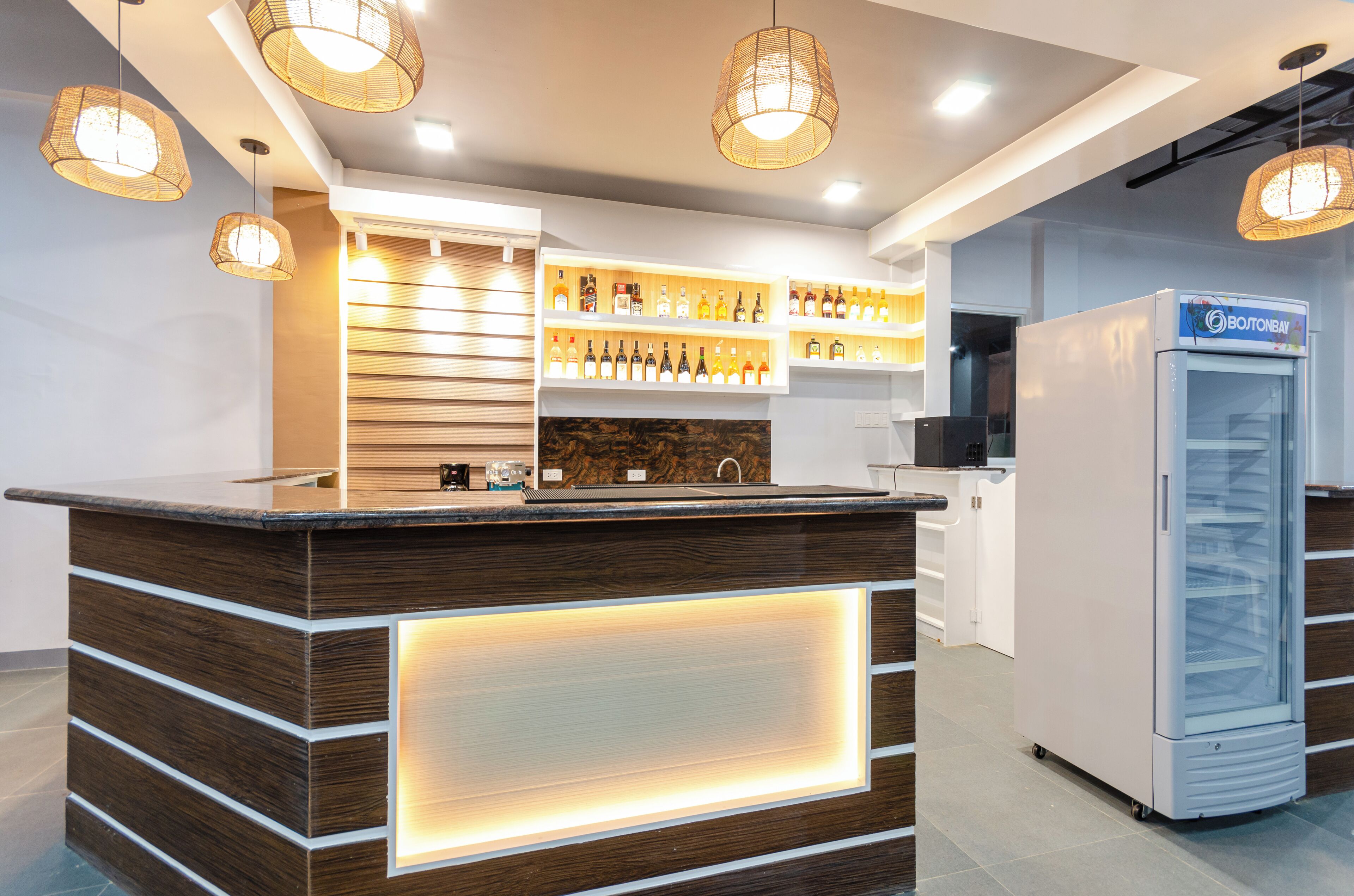 Un espace bar moderne avec un lambris en bois, un présentoir réfrigéré et des luminaires suspendus.