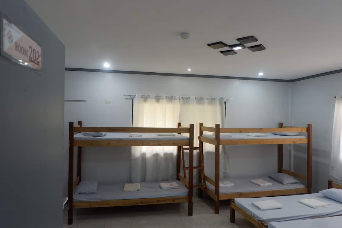 A room with bunk beds, a curtain, and a sign indicating it's room 202.
