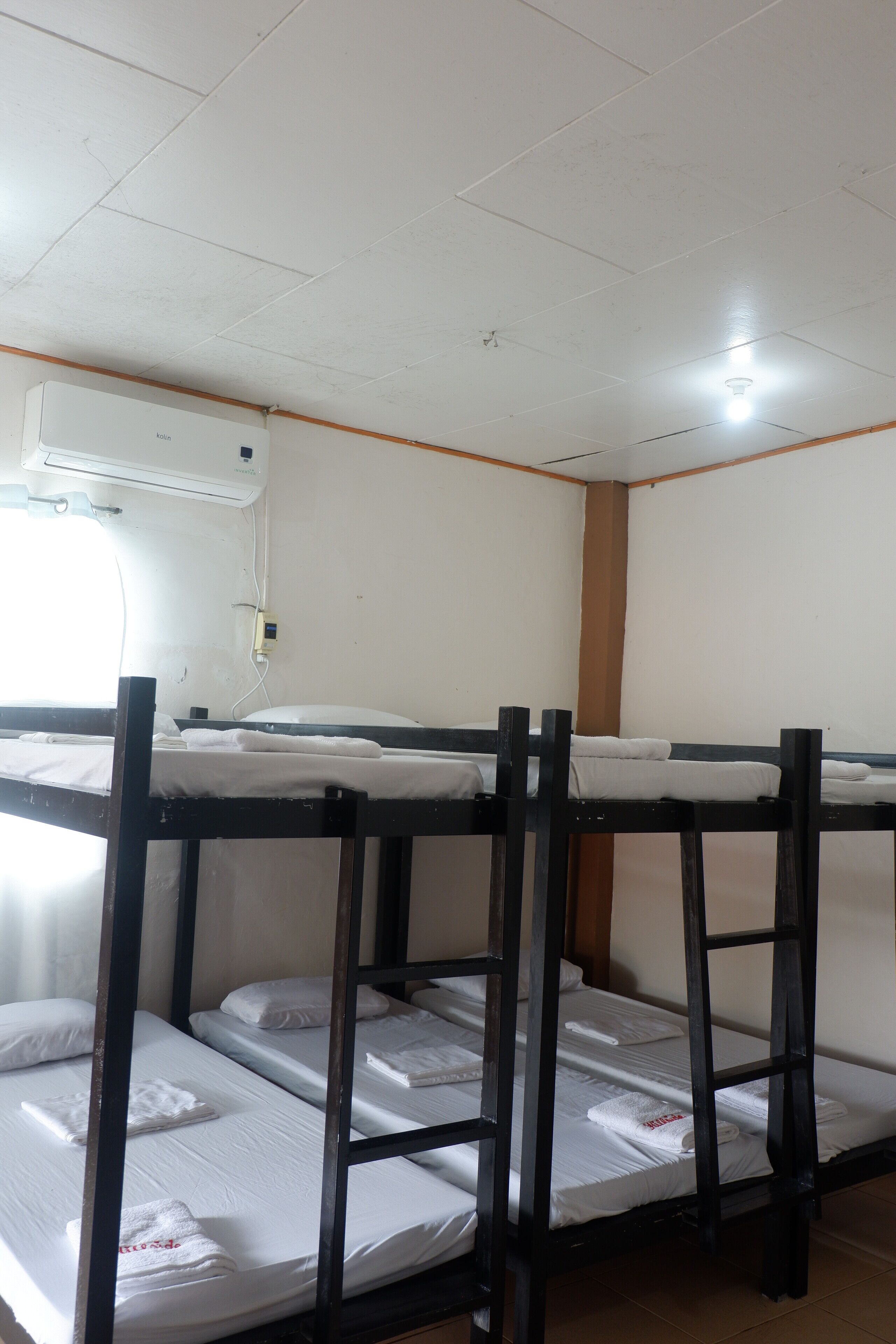 Dormitorio con literas, ropa de cama blanca y ventilador de techo.
