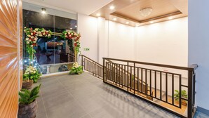 Un rebedor d'hotel modern amb una paret de fusta, una escala amb barana negra i plantes en testos.