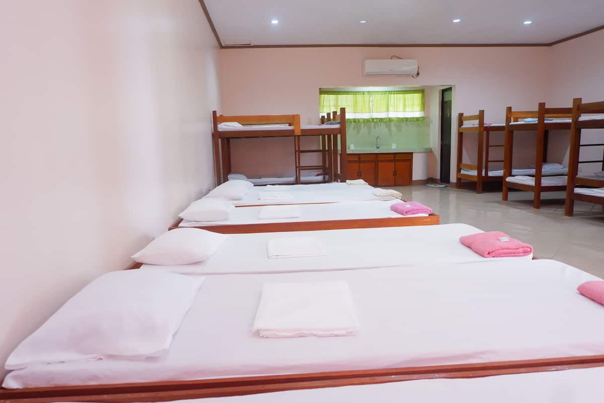 A hotel room with bunk beds, a desk, and a window with green curtains.