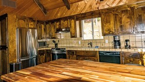 Una cocina con armarios de madera, un refrigerador de acero inoxidable, un microondas y una cafetera.