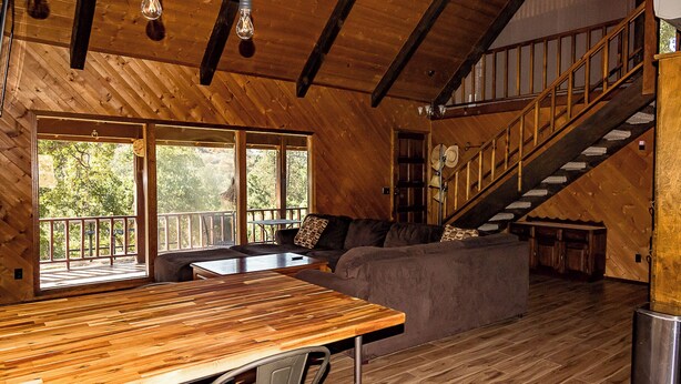 Un interior de madera con una escalera, un sofá y una mesa de comedor.