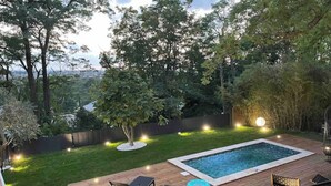 En trädgård med en pool, ett trädäck och utemöbler.