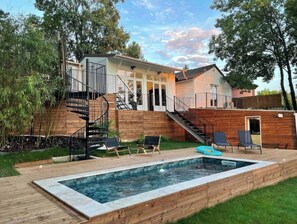 Une maison moderne dotée d’une terrasse en bois, d’une piscine et d’un escalier menant à un deuxième étage.